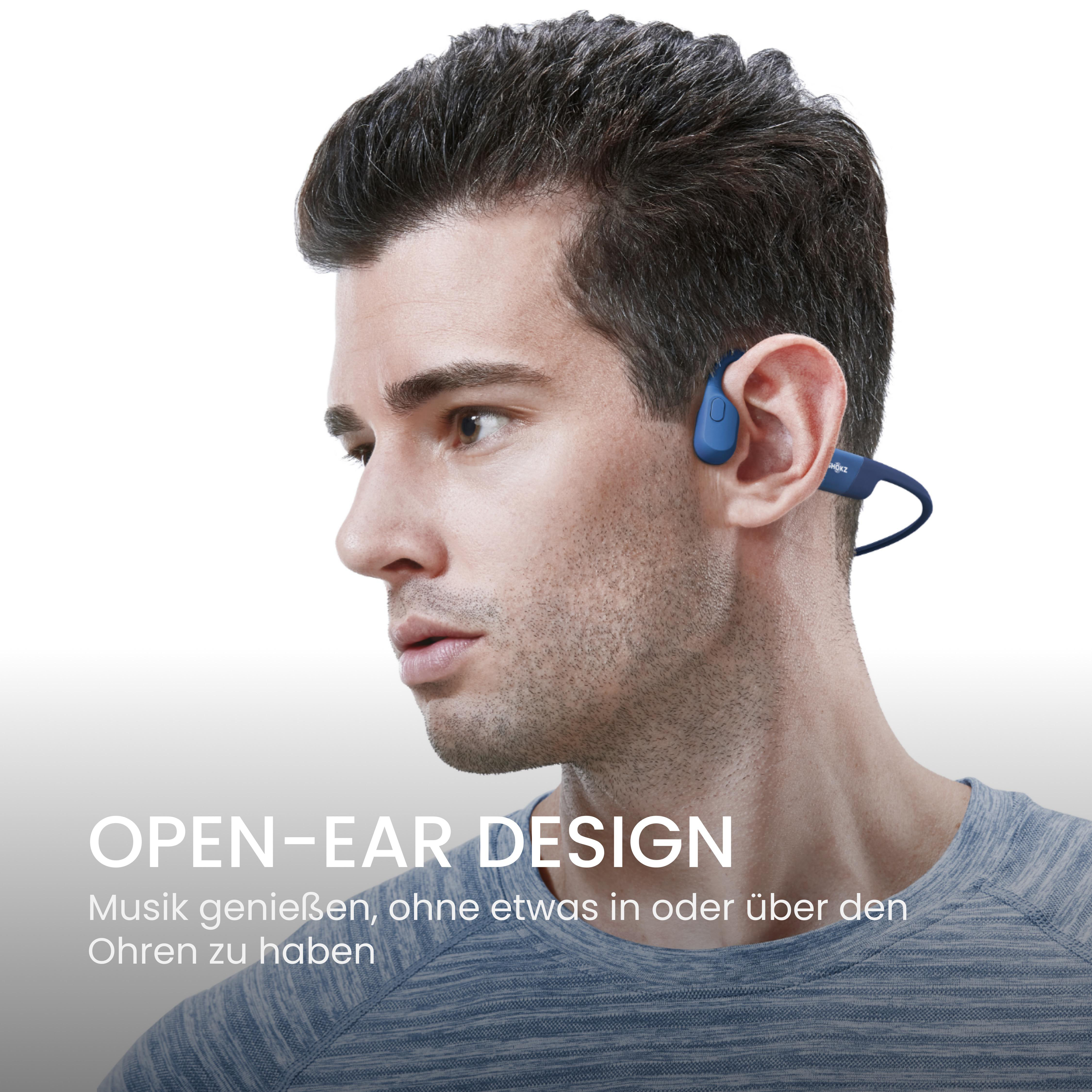Ein Mann mit blauen Open-Ear-Kopfhörern. Text: Open-Ear-Design. Musik genießen.