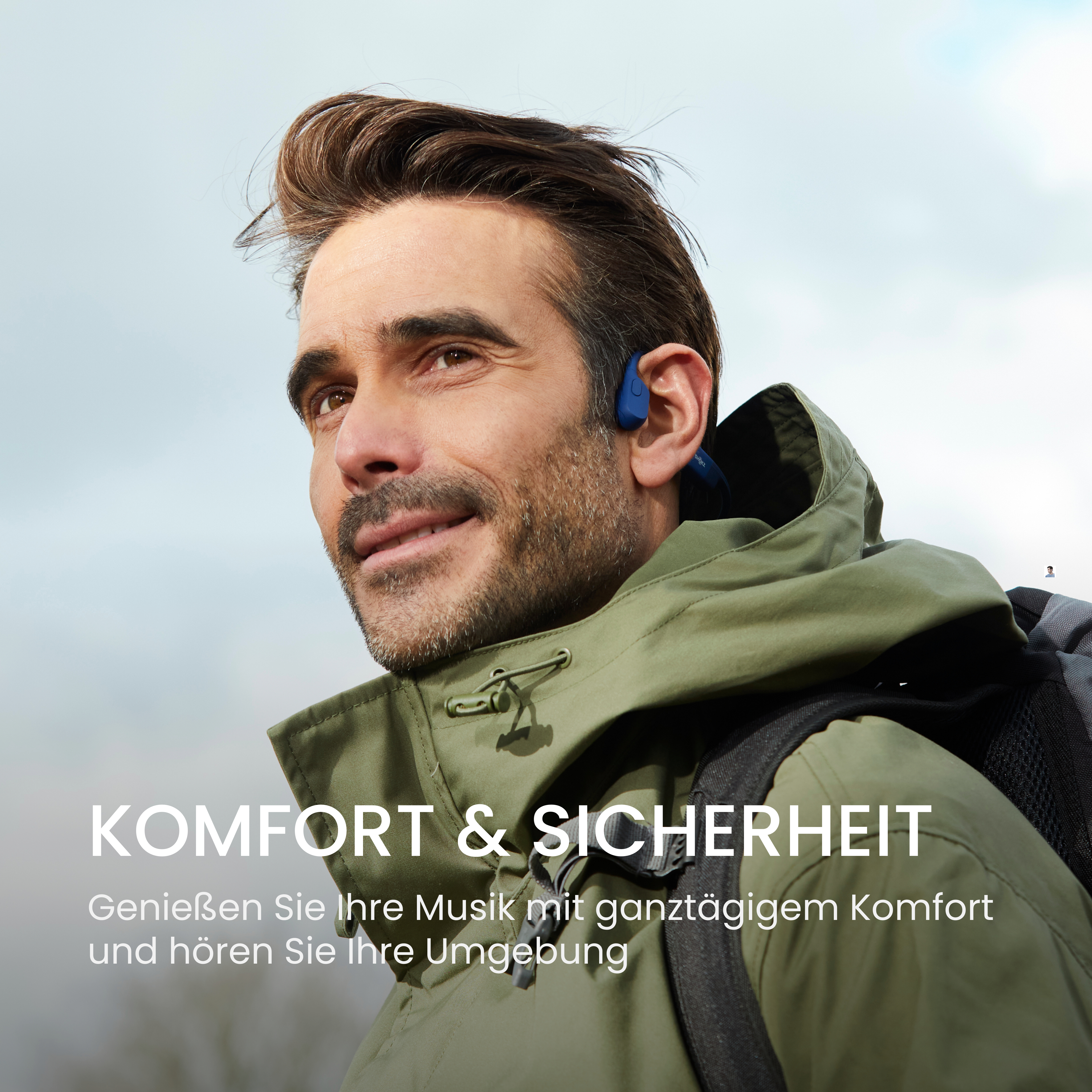 Mann mit blauem Ohrhörer, grüner Jacke und Rucksack. Text: Komfort & Sicherheit.