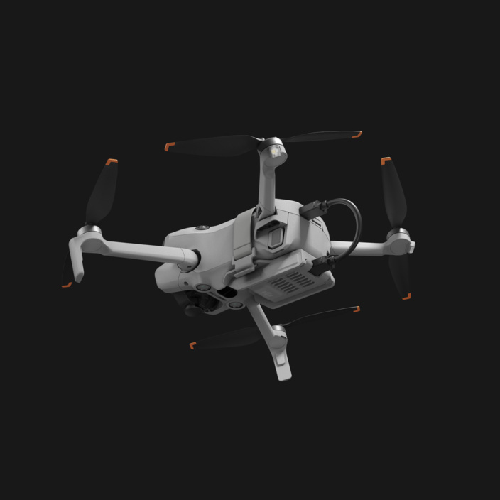 Graue Drohne mit schwarzen Propellern und orangefarbenen Akzenten.