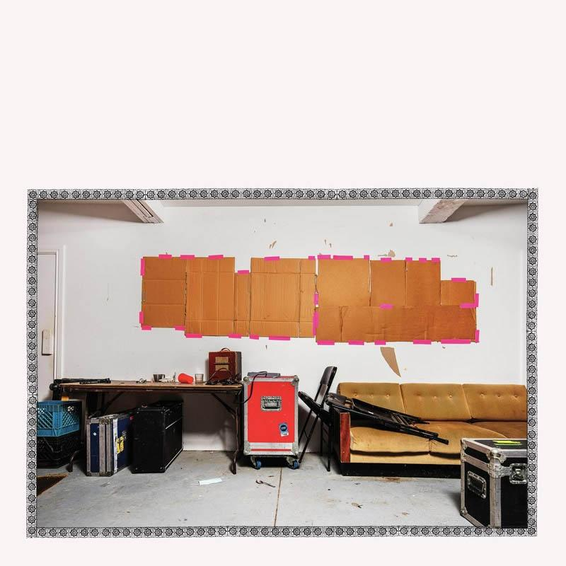 Innenaufnahme eines Raumes mit Pappe an der Wand, einem Schreibtisch, einem Sofa und Ausrüstung.