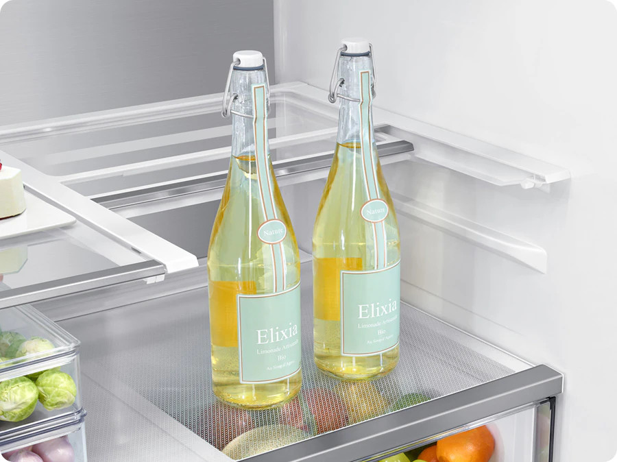 Dwie butelki z żółtym płynem na półce w lodówce.