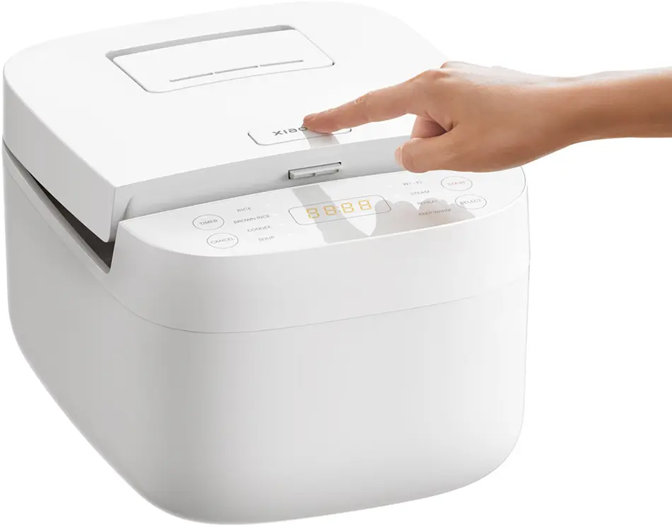 Una mano preme un pulsante su una cuociriso bianca con display digitale.