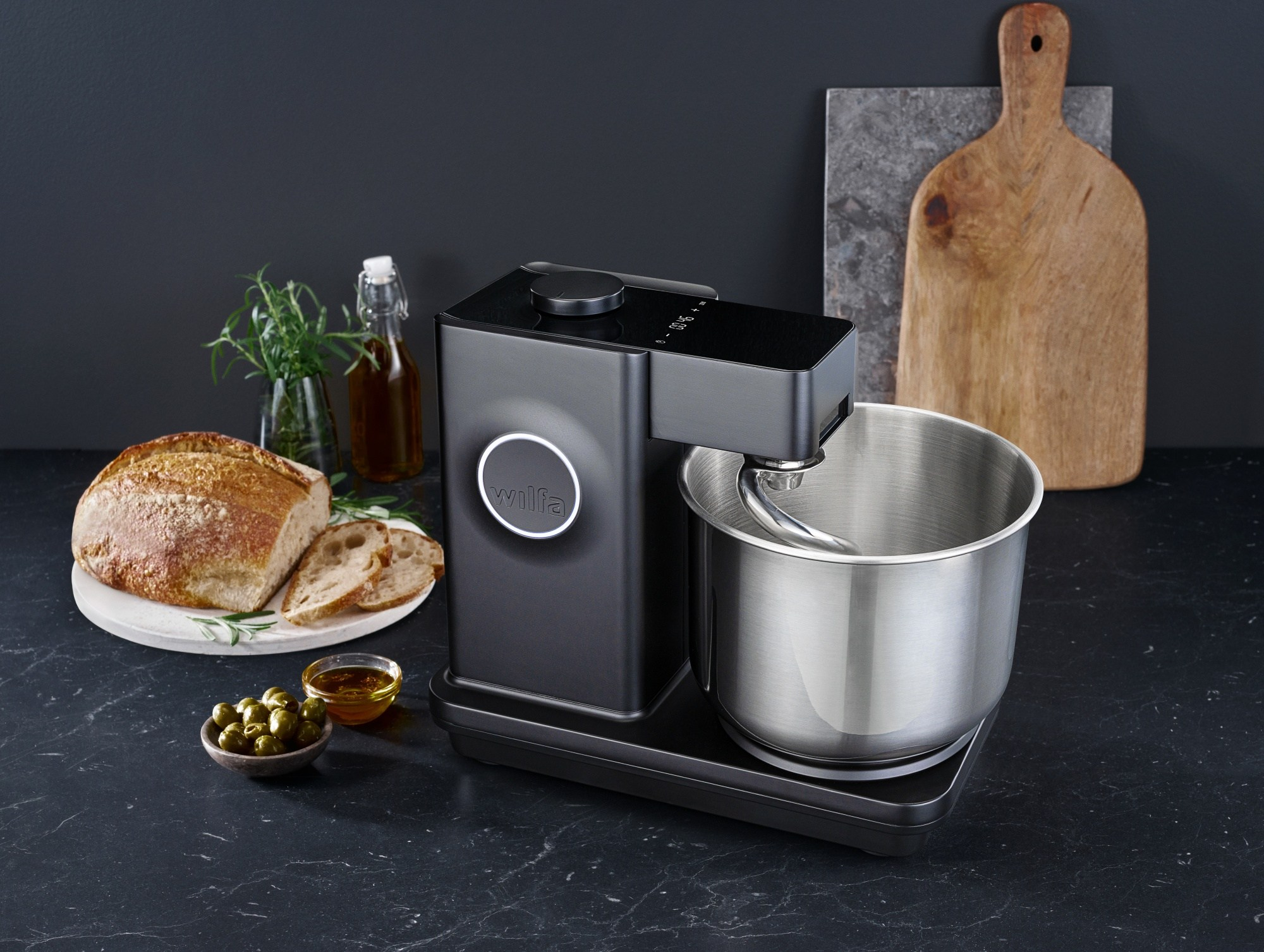 Schwarzer Küchenmixer mit Brot, Öl und Oliven.