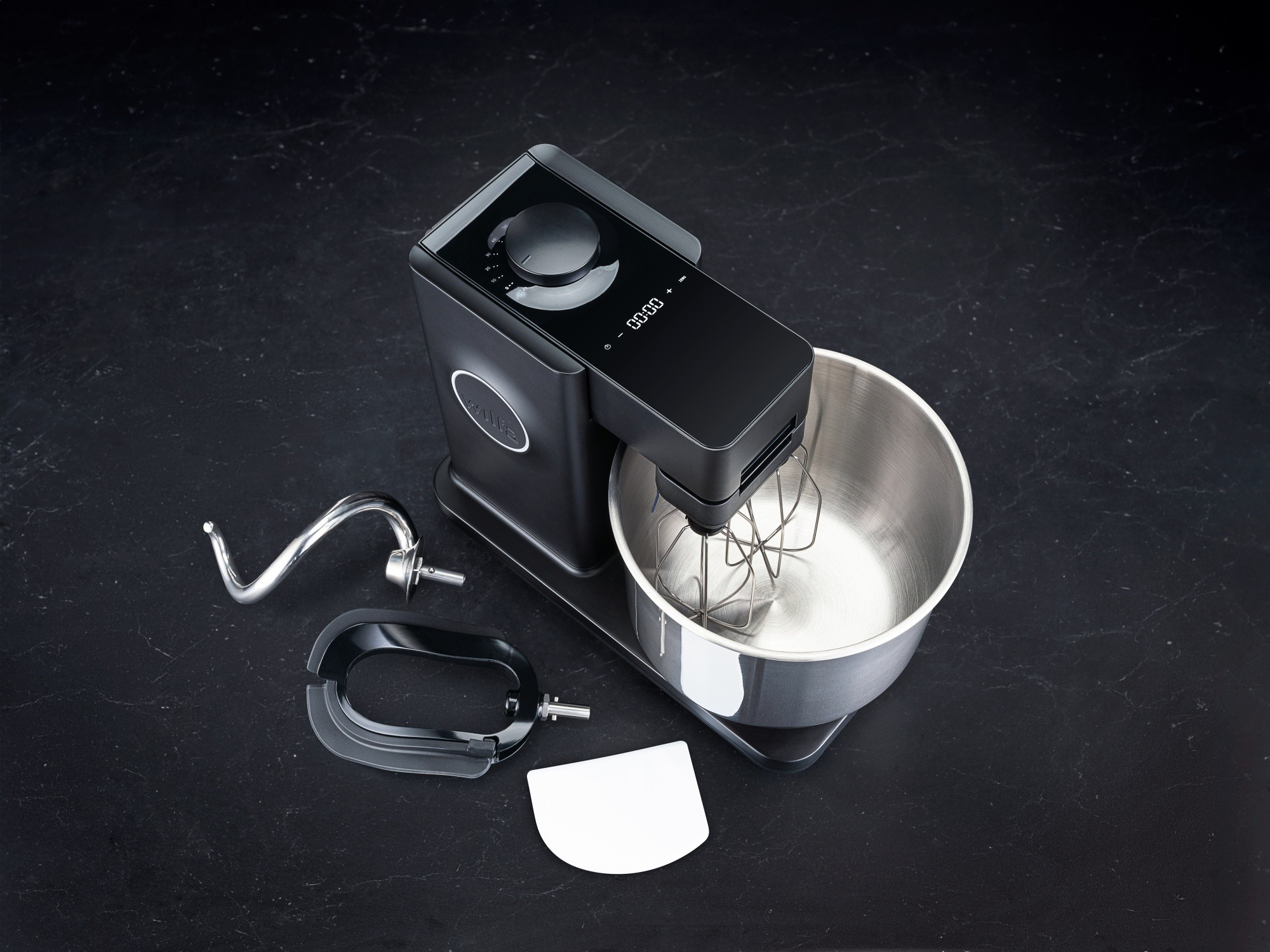 Schwarzer Küchenmixer mit Aufsätzen auf dunkler, strukturierter Oberfläche.