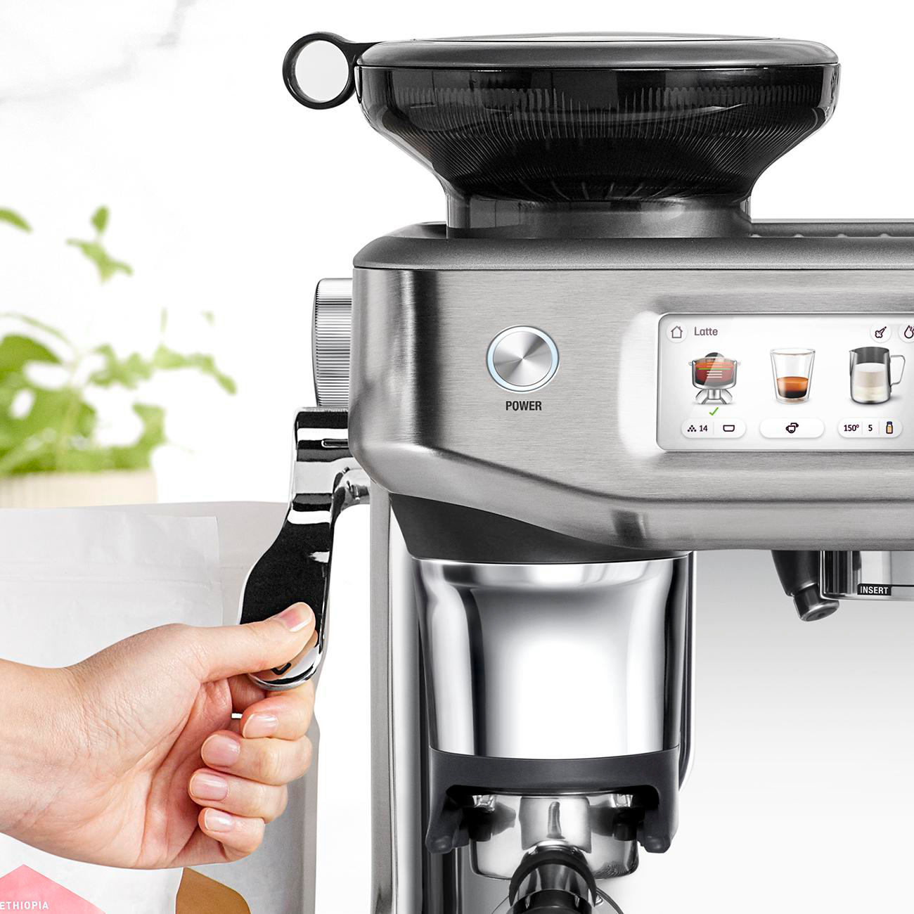 Eine Hand bedient eine Kaffeemaschine. Die Maschine ist silber und schwarz.