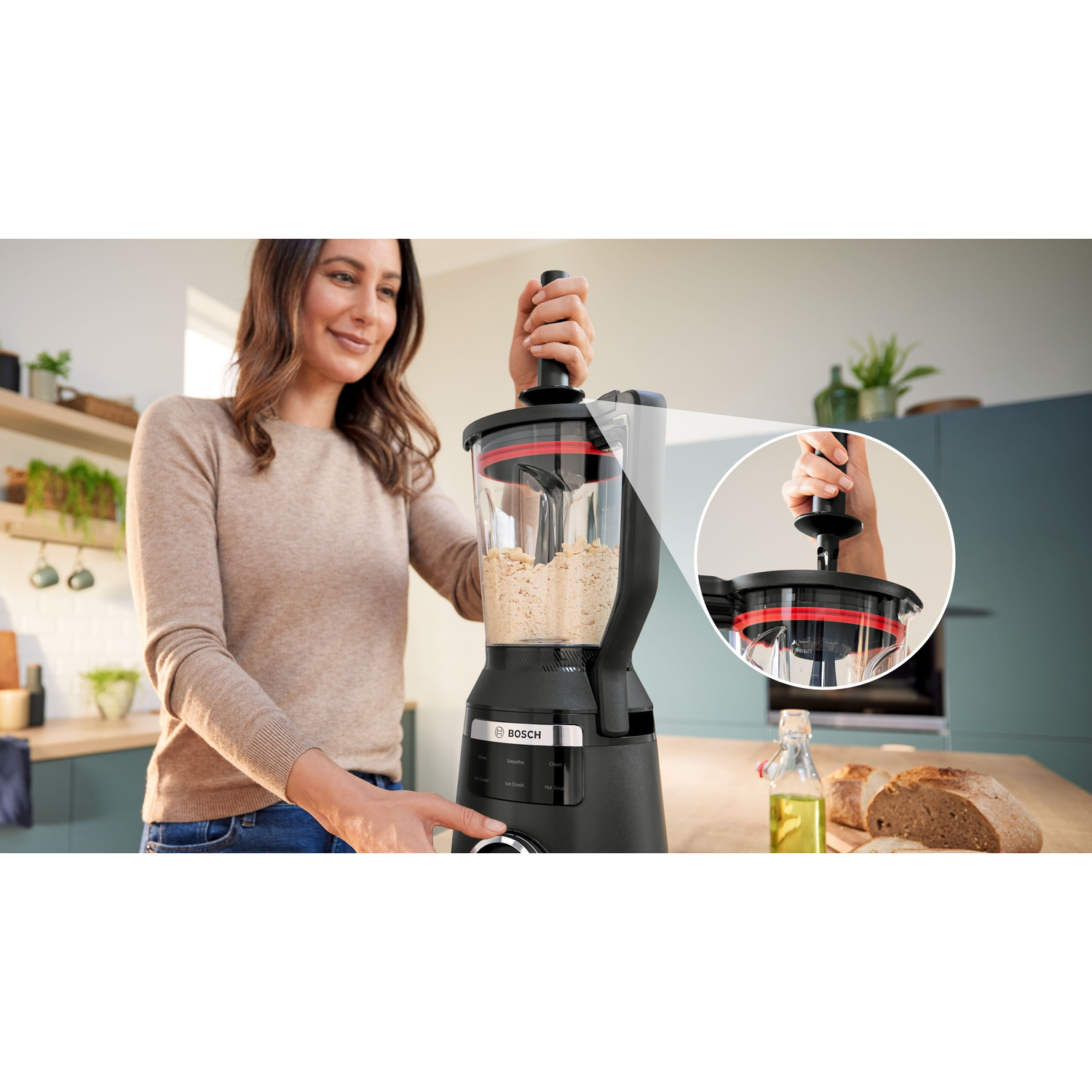 A woman using a black Bosch food processor in a kitchen.