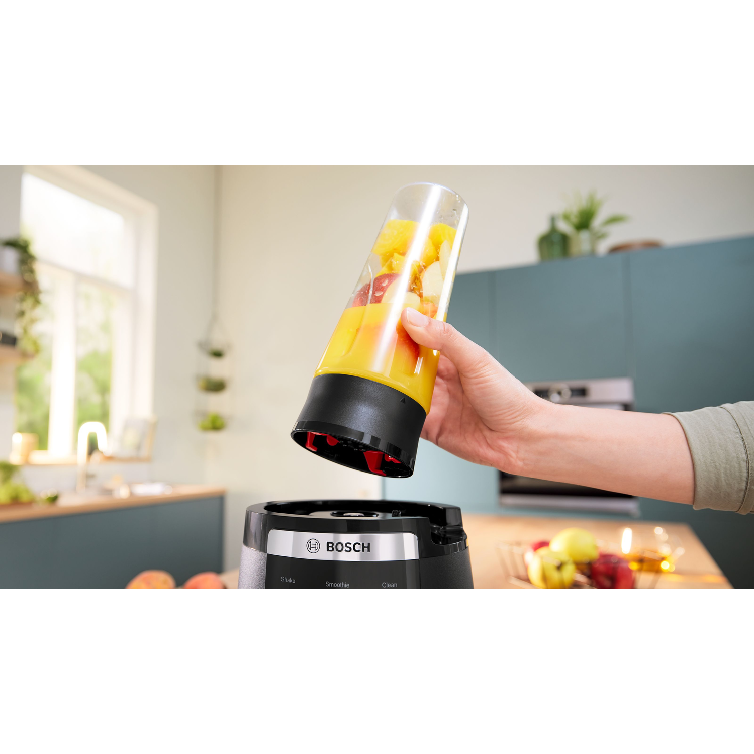 A hand pouring fruit juice into a blender, with kitchen background.