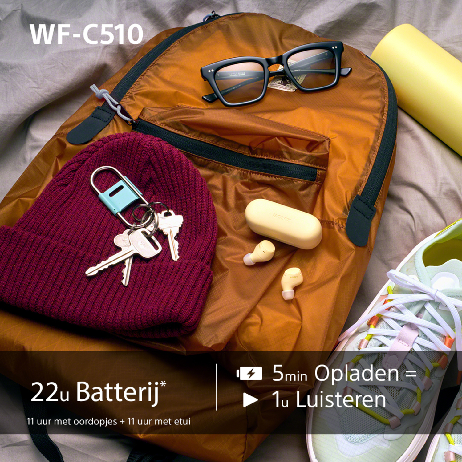 Een tas met accessoires: bril, oordopjes, sleutels en een muts. Tekst: WF-C510. 22u Batterij*.