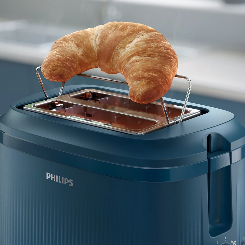 Egy kék Philips kenyérpirító, tetején egy pirított croissant-val.