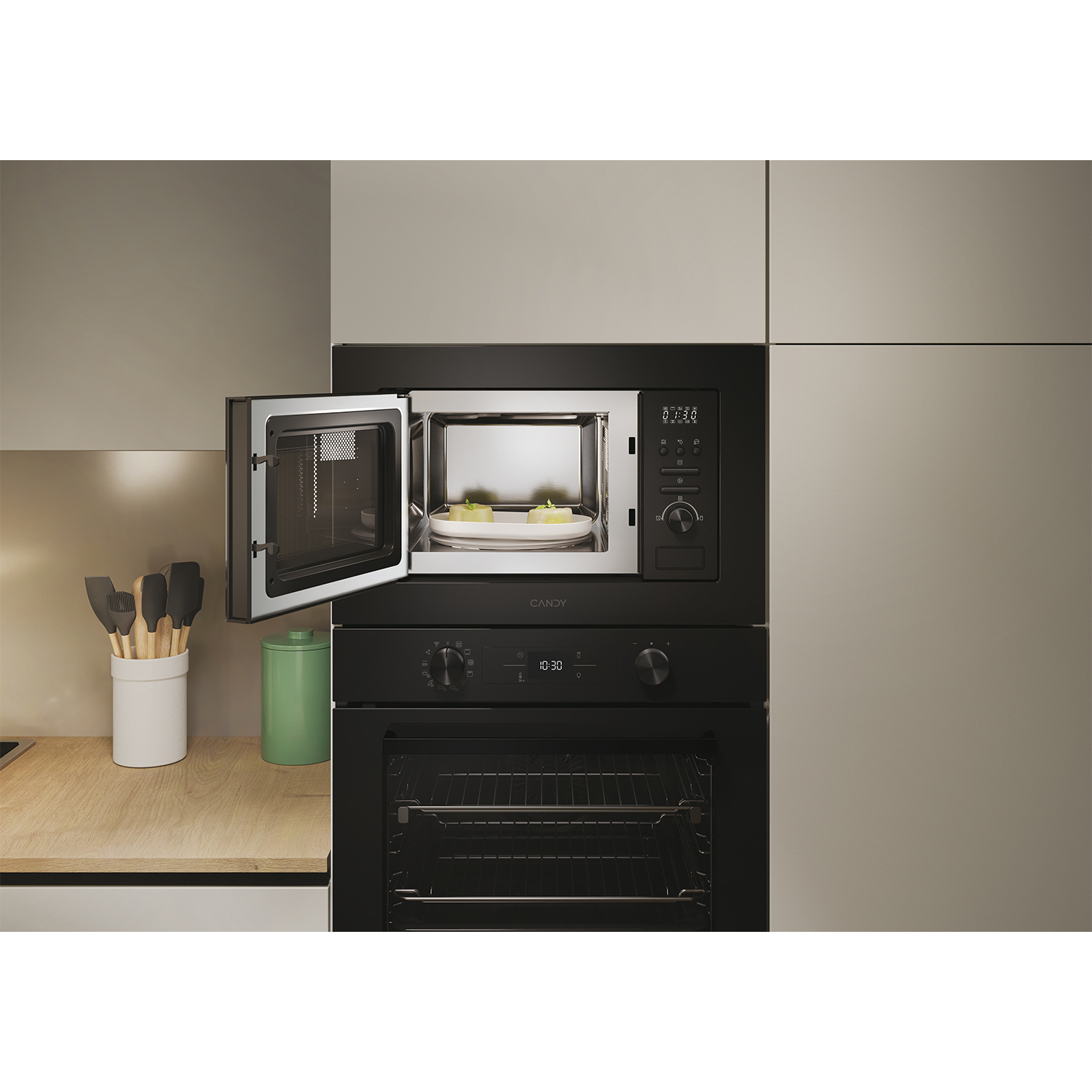 Un forno a microonde e un forno sono impilati. Porta del microonde aperta, che mostra cibo.