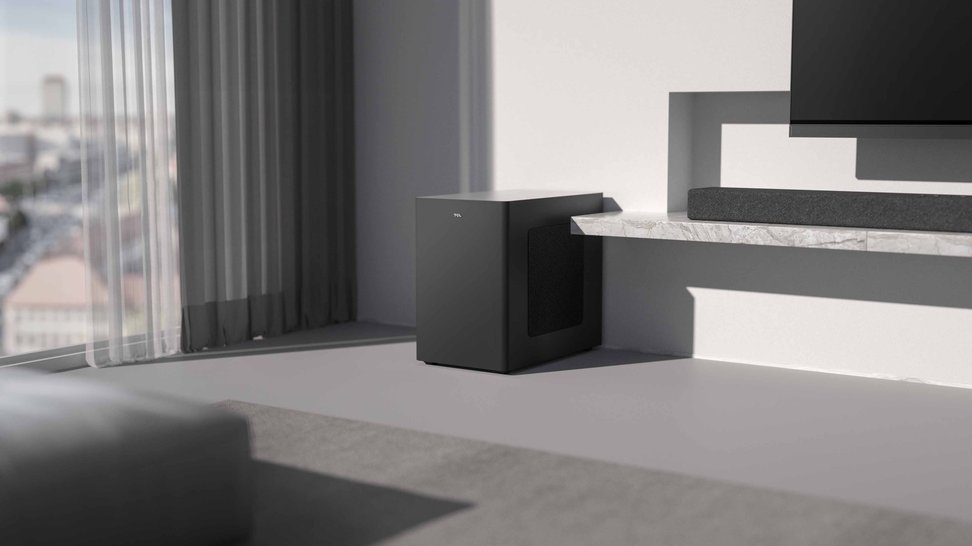 Modern bir oturma odasında bir TV ve soundbar'ın yanında TCL subwoofer.