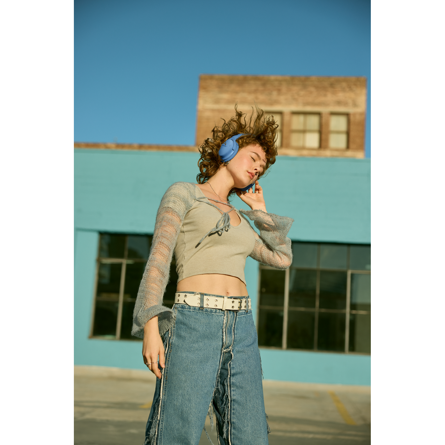 A woman with blue headphones and denim jeans.