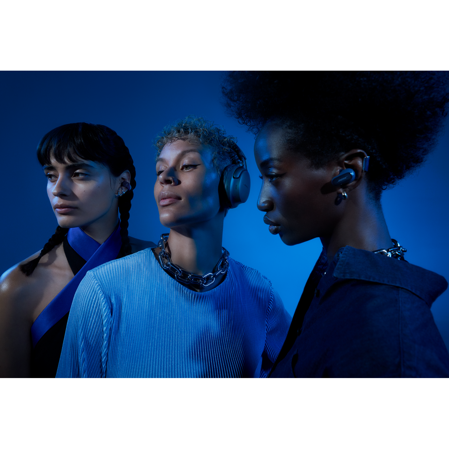 Three models in blue. They are wearing headphones. Dark blue background.