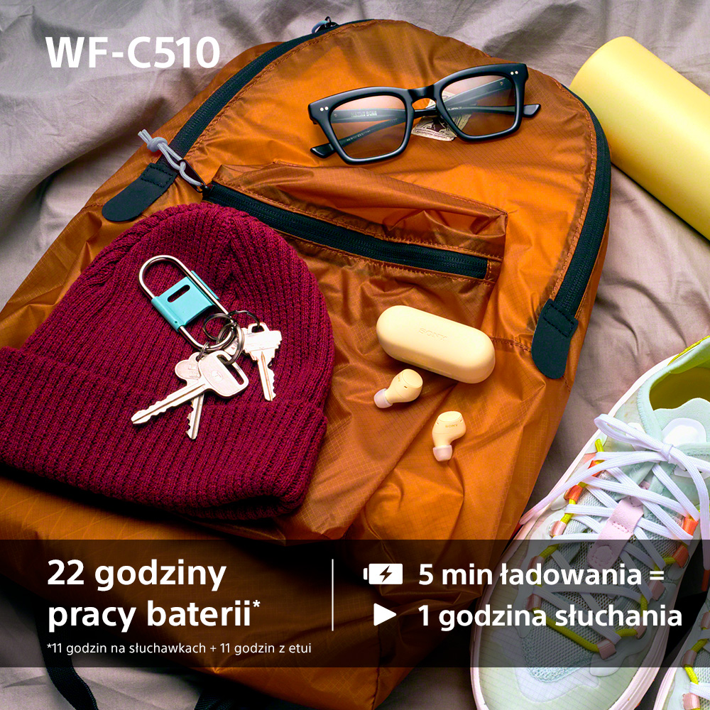 Pomarańczowy plecak z okularami, kluczami, czapką, słuchawkami i butem. Tekst: 22h bateria, 5 min ładowania = 1h słuchania.