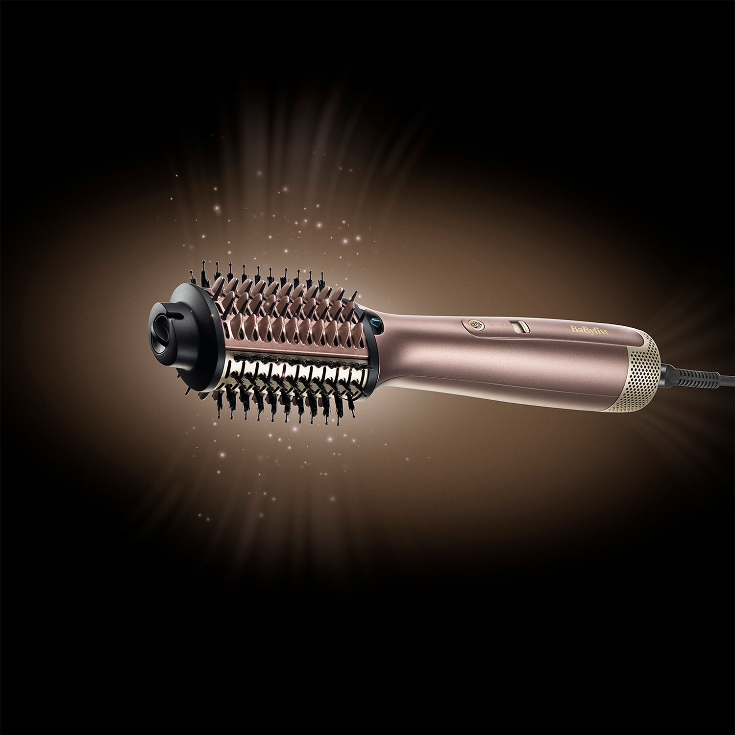 Spazzola per lo styling dei capelli con finitura oro rosa, su sfondo scuro con effetti luce.