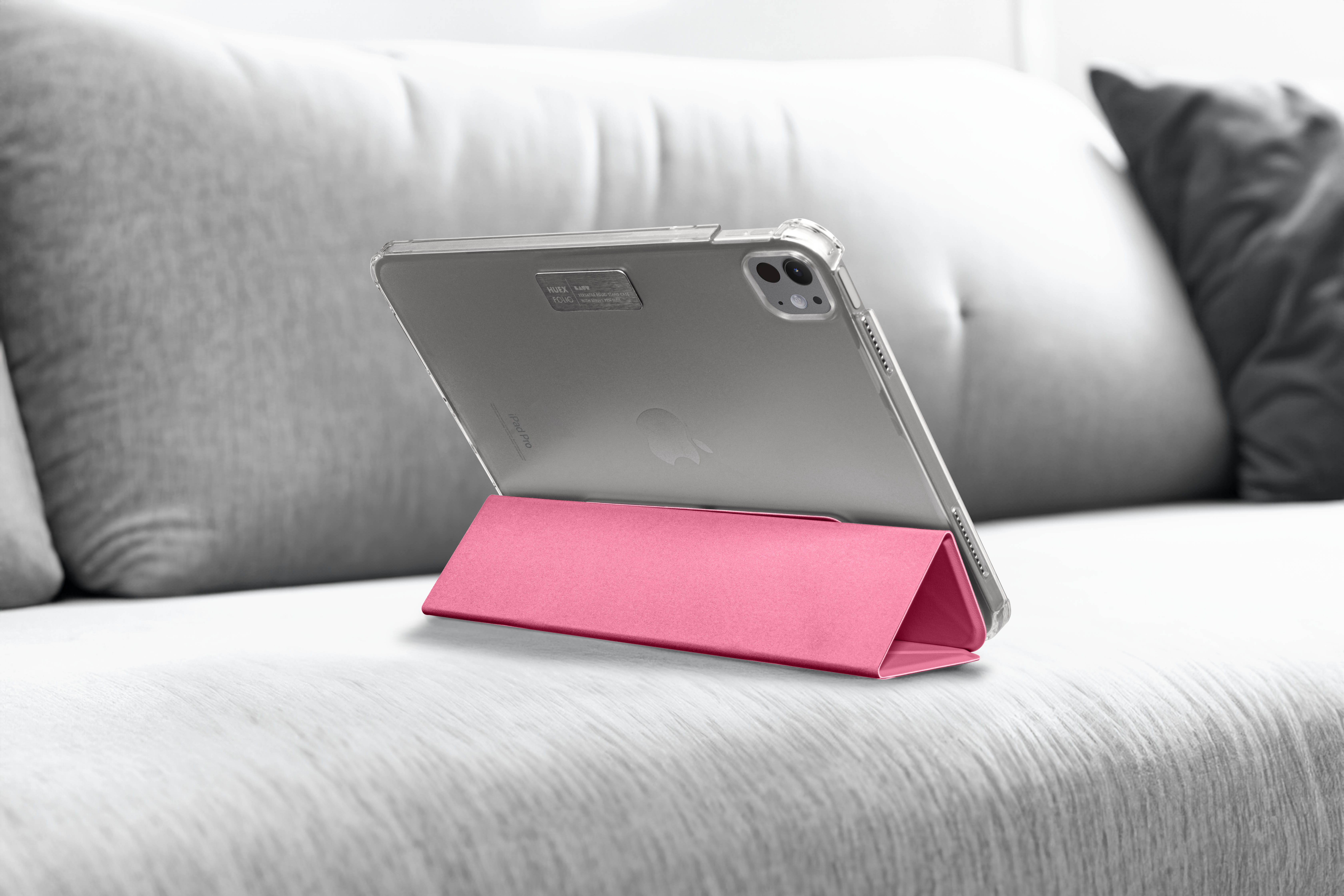 Tablet auf rosa Hülle auf einer Couch. Hülle angewinkelt, Bildschirm sichtbar.