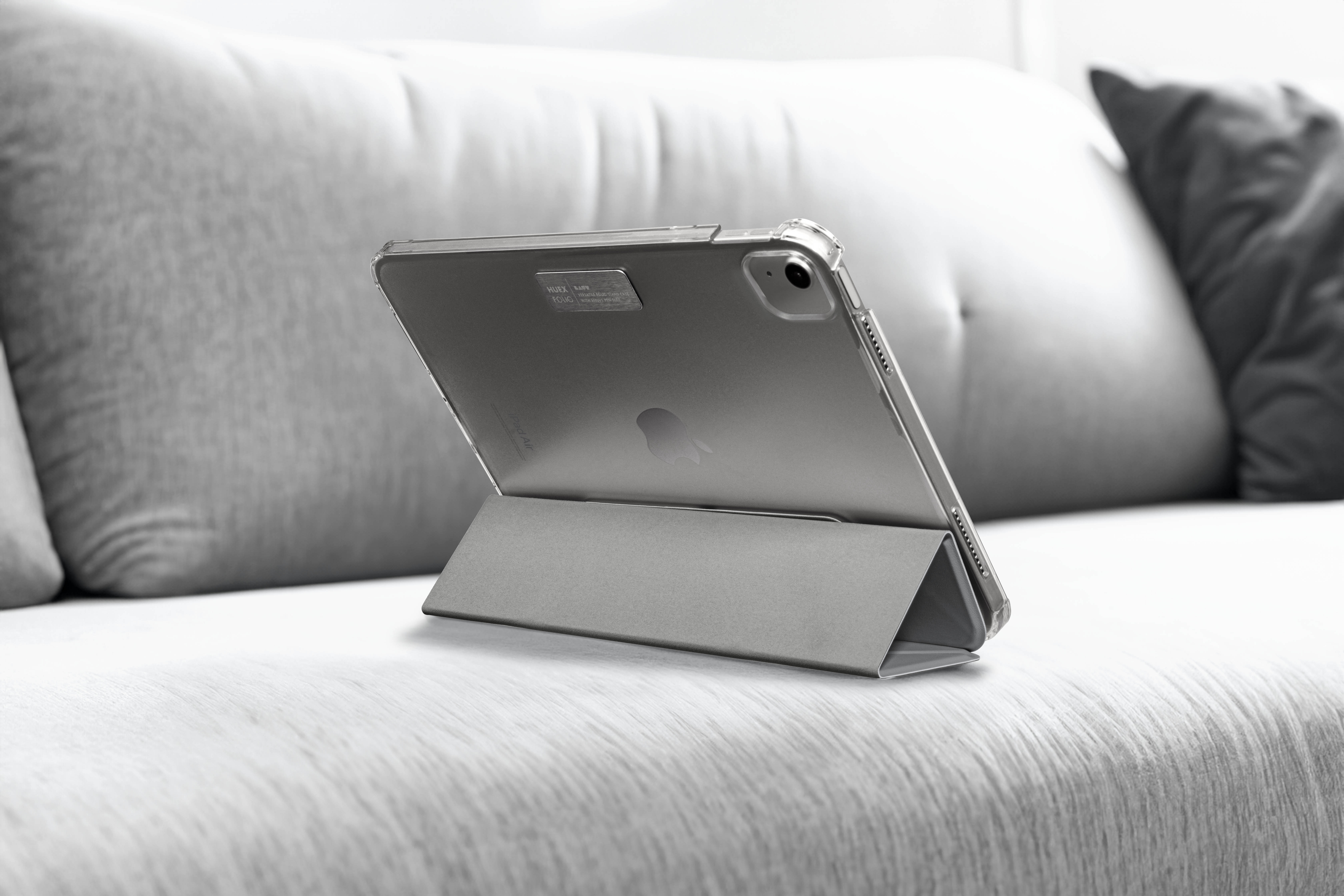 Ein iPad wird von einem Ständer auf einem grauen Sofa gehalten. Der Bildschirm ist leer.