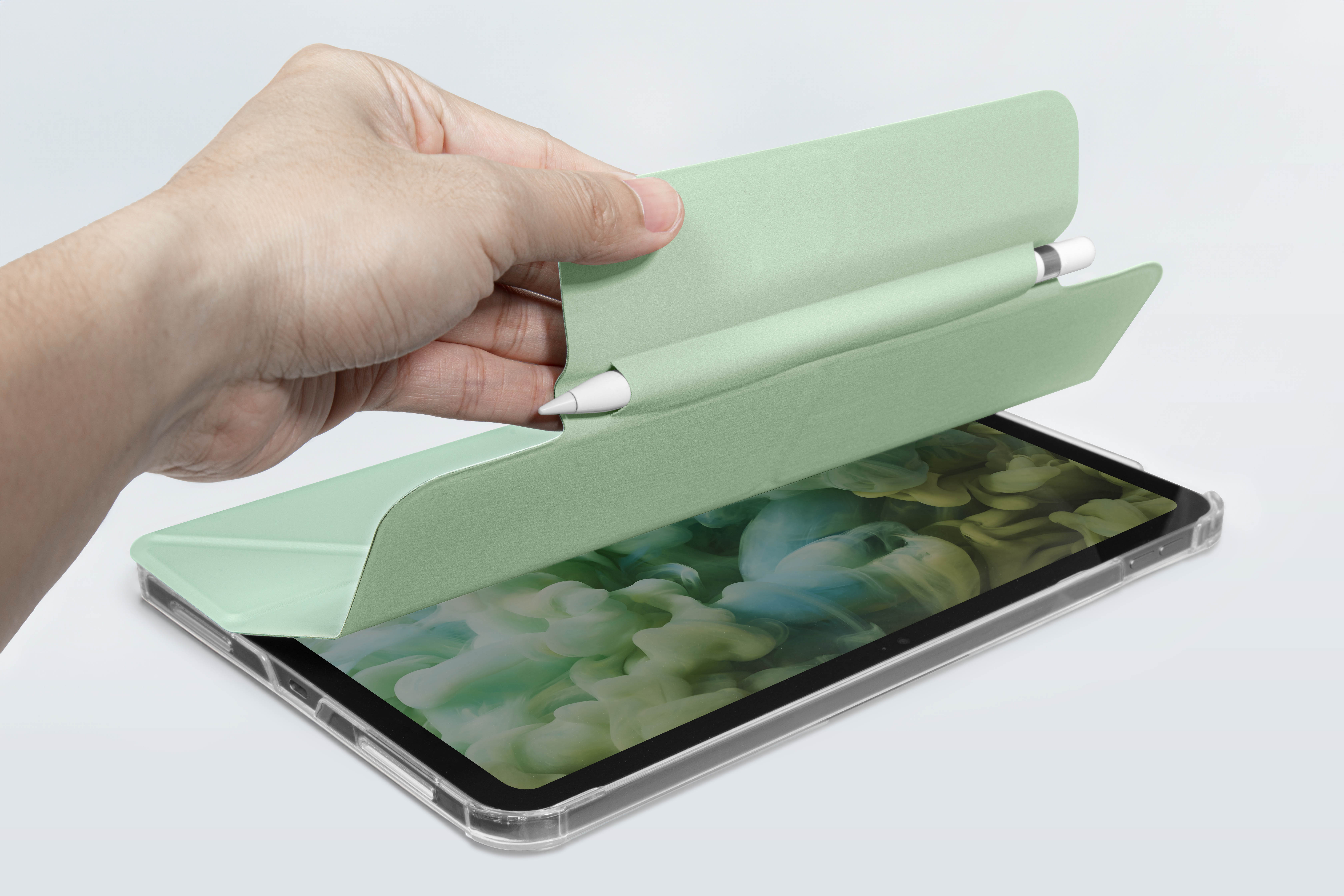 Die Hand einer Person öffnet eine grüne Hülle mit einem Bleistift und einem Tablet.