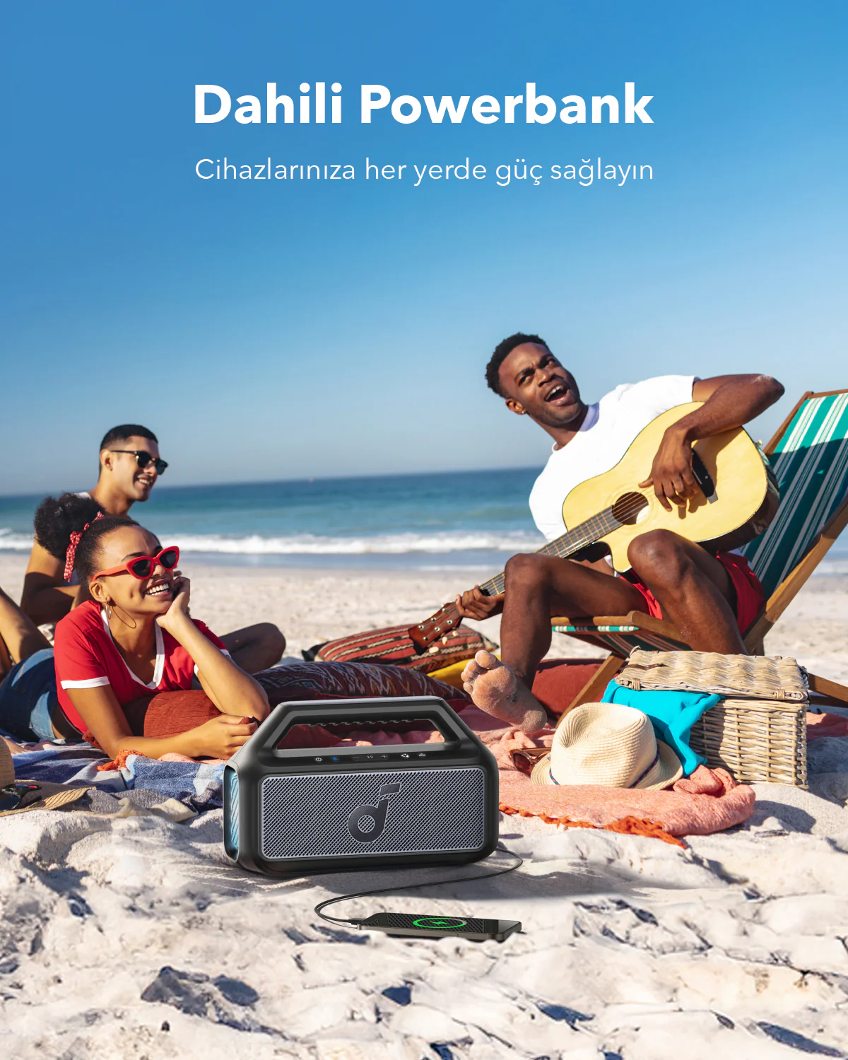 Sahilde powerbank ile insanlar ve gitar çalan bir adam.