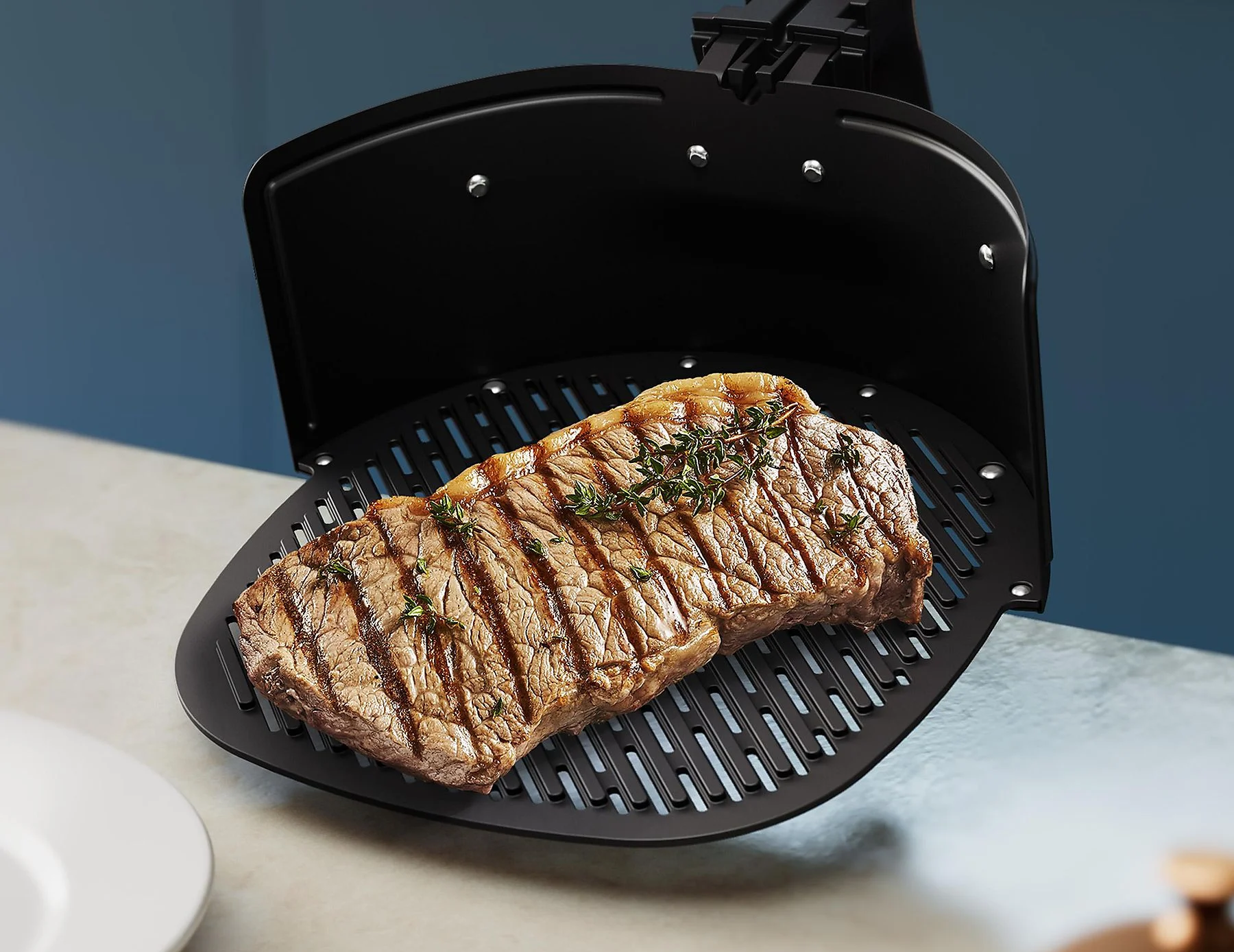 Grillezett steak egy fekete serpenyőben egy fekete légfritőzben.