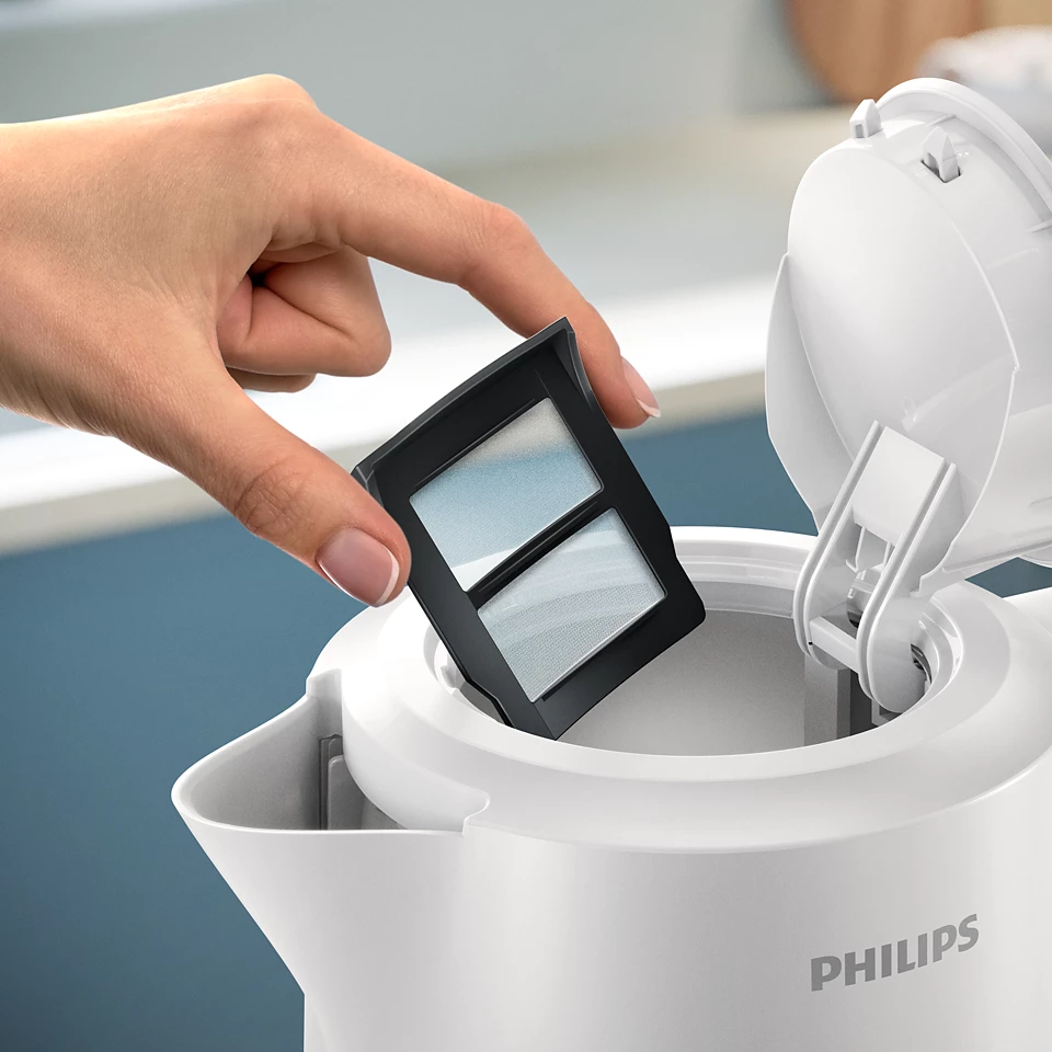 Kéz, ami egy fehér Philips vízforraló szűrőjét tartja. Nyitott fedél felül.