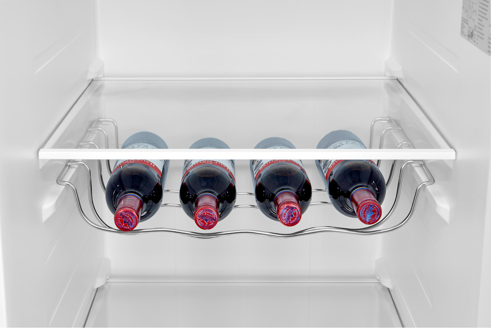 Bouteilles de vin dans un réfrigérateur. Quatre bouteilles sur une étagère métallique.