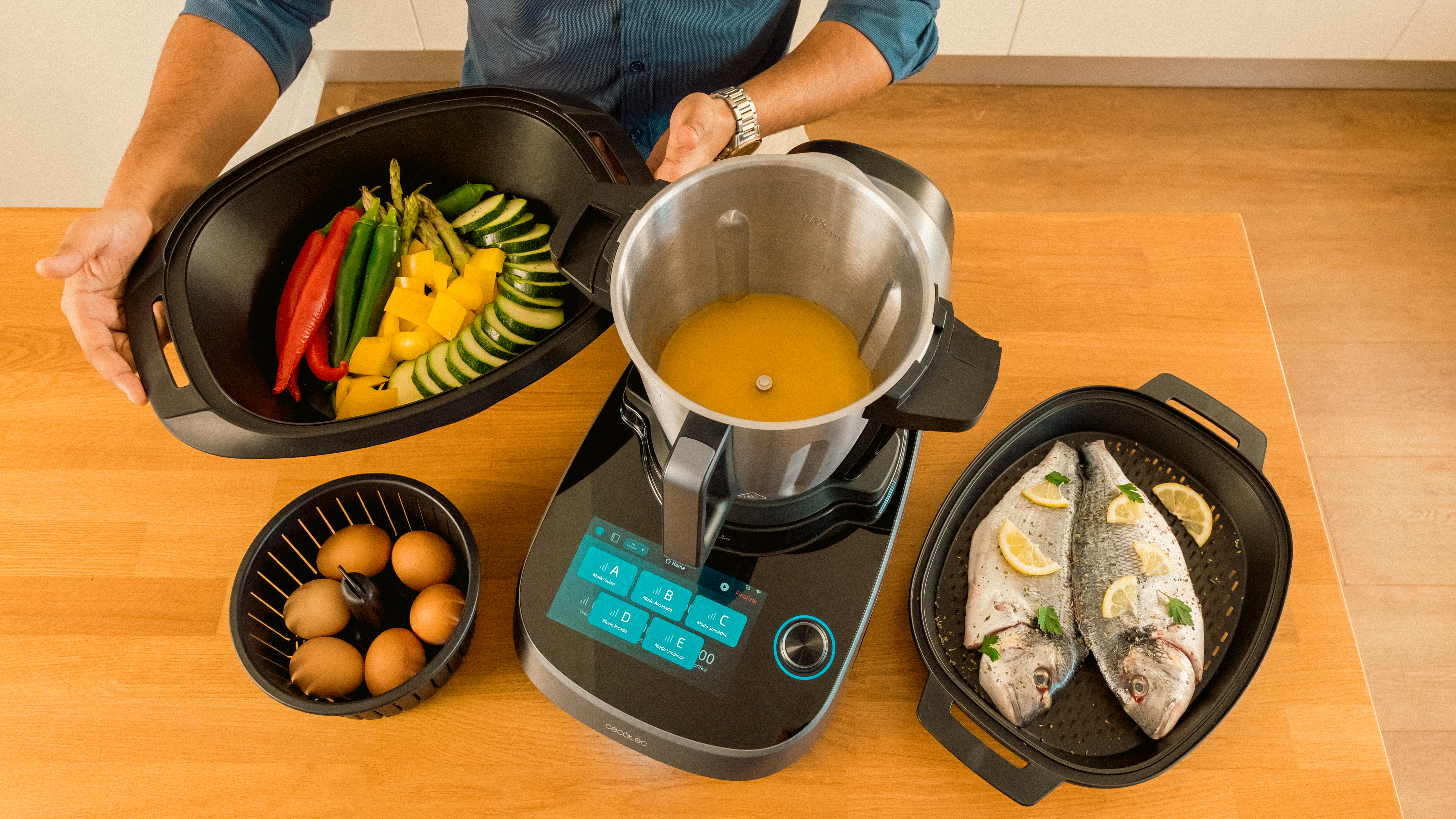 Configuración de cocina con comida en cuencos y un procesador de alimentos sobre una mesa.