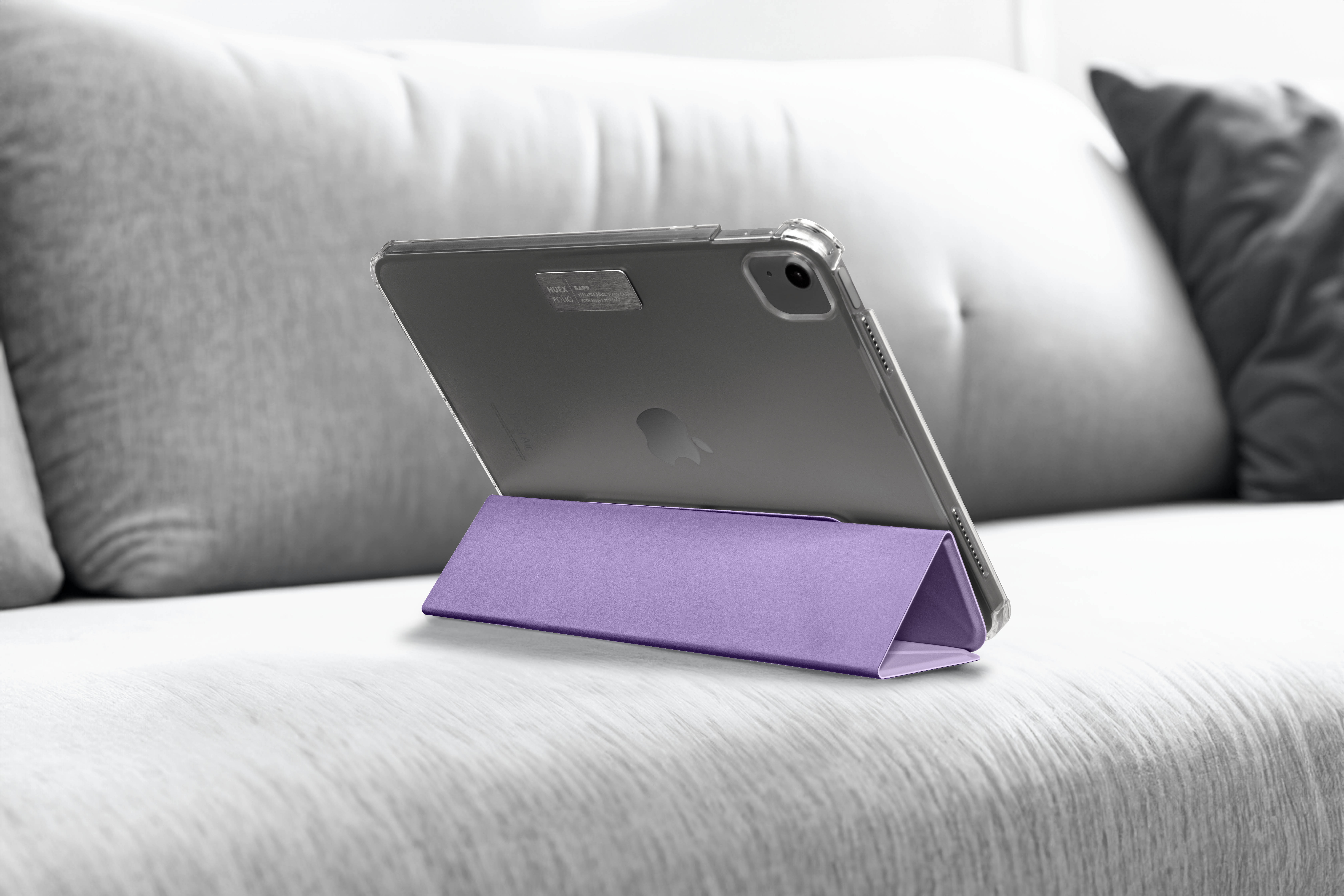 Tablet in lila Ständer auf Sofa, mit transparenter Schutzhülle.