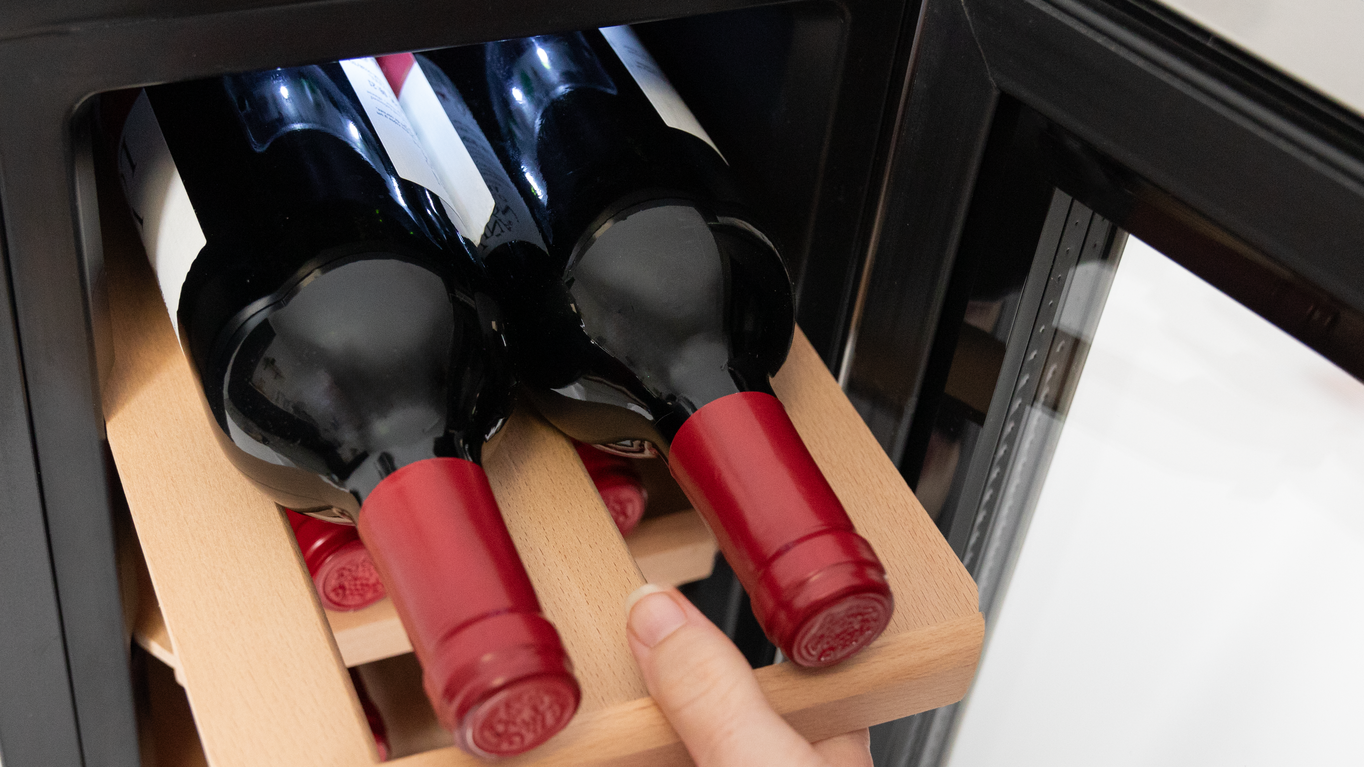 Botellas de vino en una nevera. Botellas de vino tinto en estantes de madera.