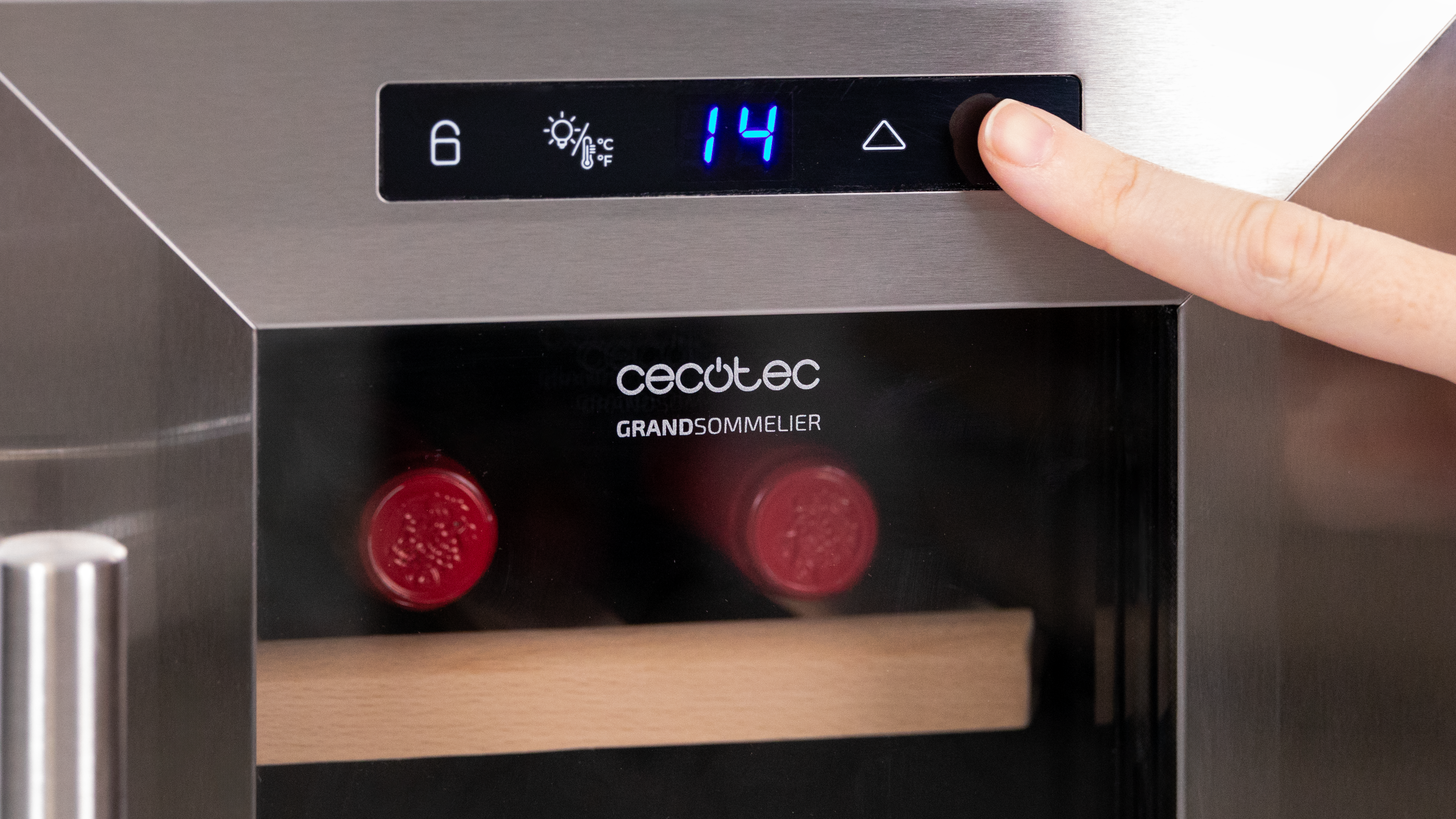 Primer plano de una vinoteca plateada con un dedo pulsando un botón mostrando la temperatura.