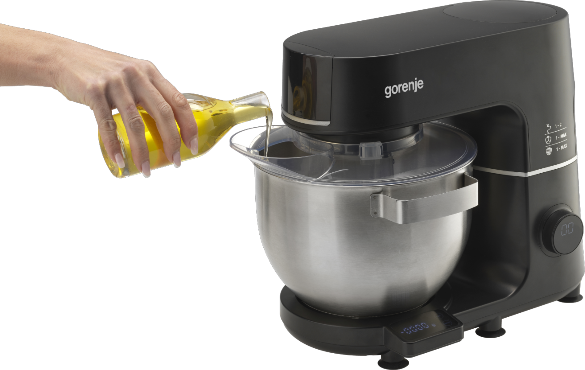 Kéz olajat önt a Gorenje konyhai mixerbe. Fekete mixer, rozsdamentes acél tál.