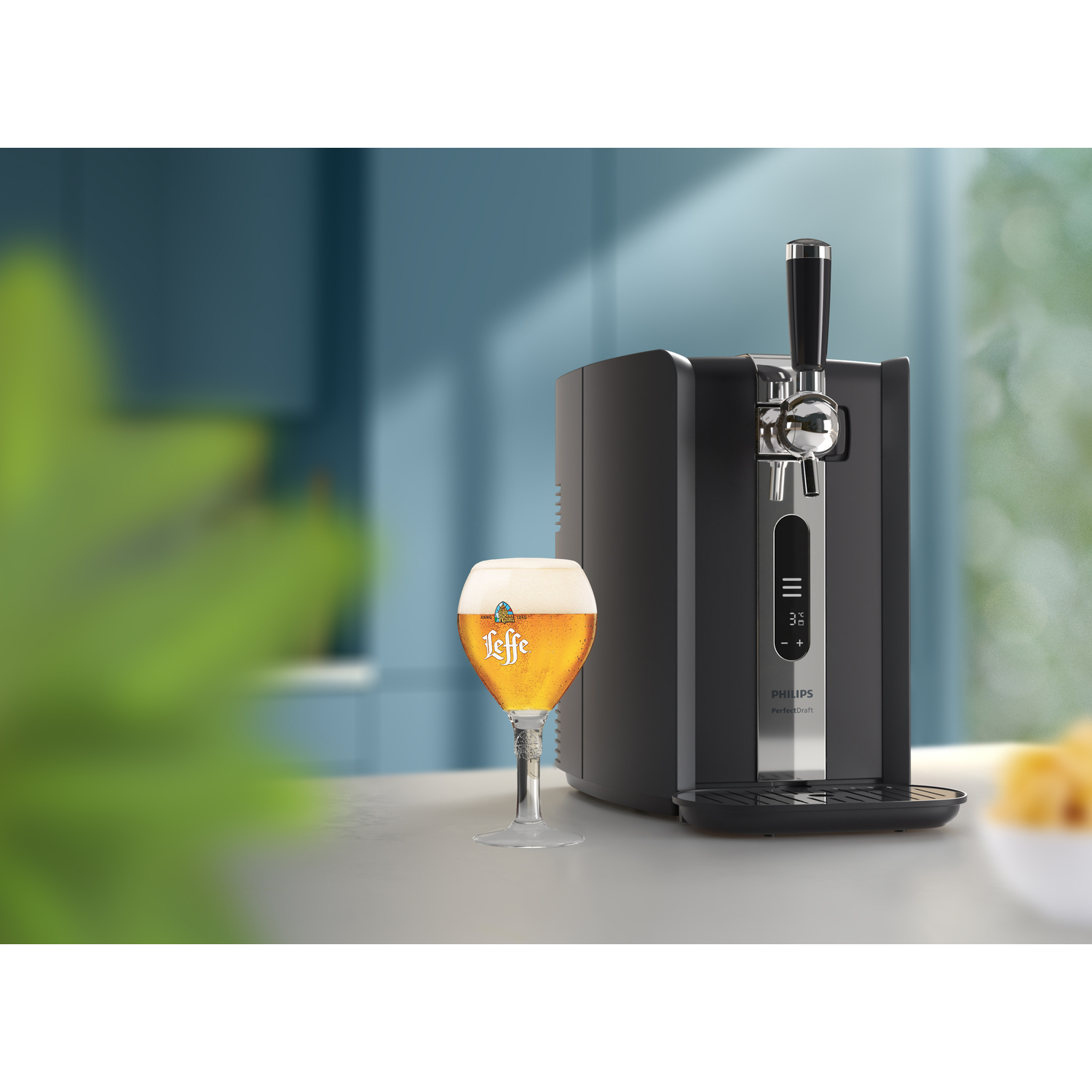Zwarte tap met een glas bier. Groene plant op de voorgrond.