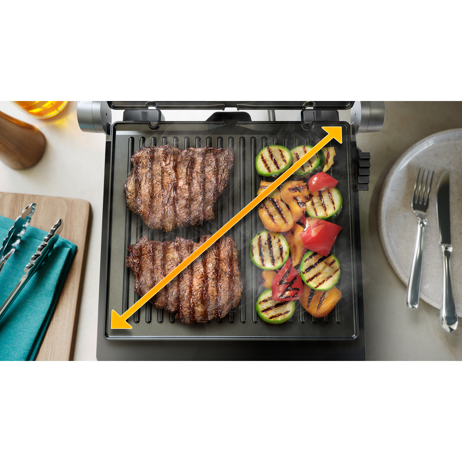 Grill met twee steaks en gegrilde groenten, met gele pijlen die het grilloppervlak aangeven.