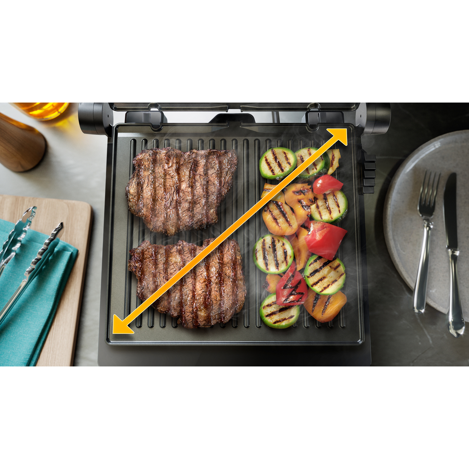 Gril avec deux steaks et légumes grillés. Flèche indique la zone de cuisson.