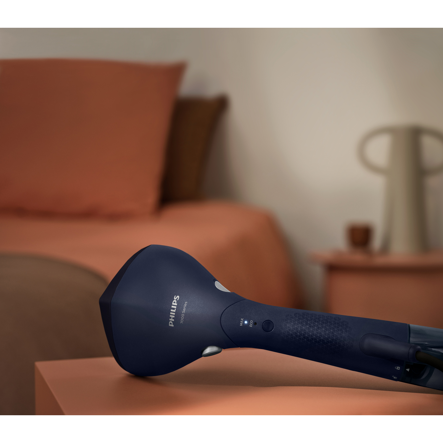 A dark blue Philips handheld steamer on a wooden surface, with a blurred background.