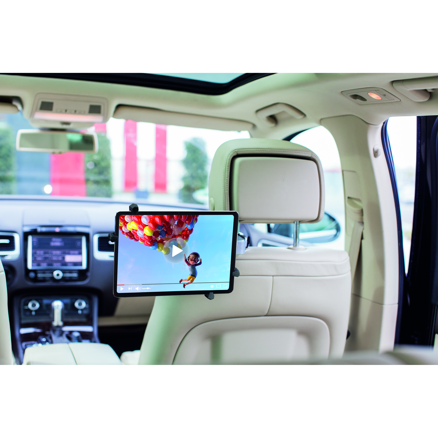 Tablet mounted on a car seat, playing a video of a cartoon with colorful balloons, interior visible.