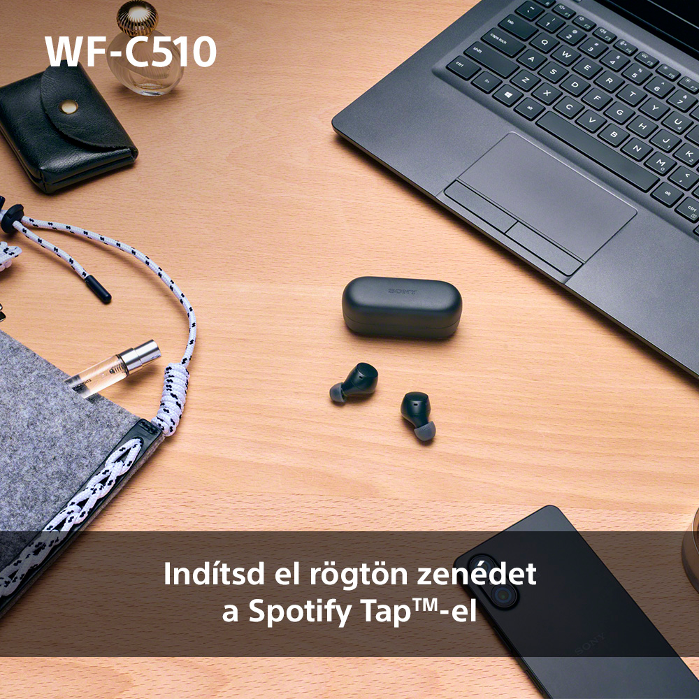 Fülhallgatók, töltőtok és kiegészítők egy faasztalon. Szöveg: Spotify Tap.
