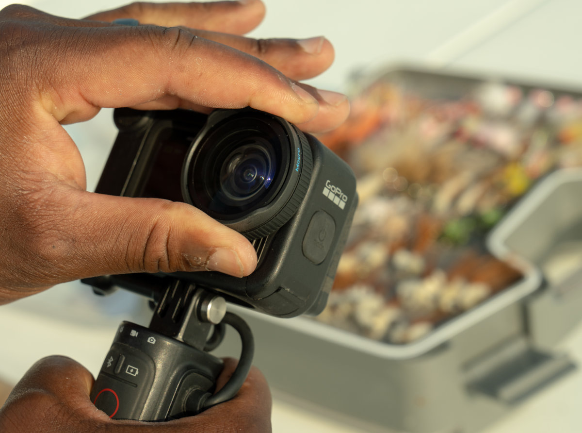 Dłonie trzymające kamerę GoPro z ekranem pokazującym tacę z jedzeniem.