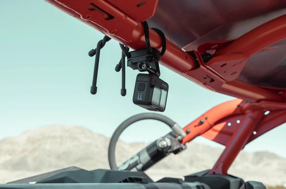 Kamera GoPro zamontowana na klatce bezpieczeństwa czerwonego pojazdu, na tle jasnego nieba.