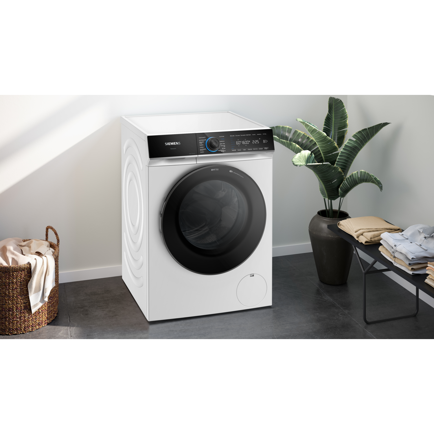 A white washing machine with a dark door, next to a plant and basket.