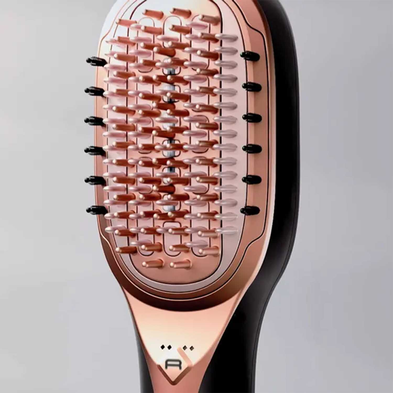 Spazzola lisciante per capelli con design oro rosa e nero, primo piano.