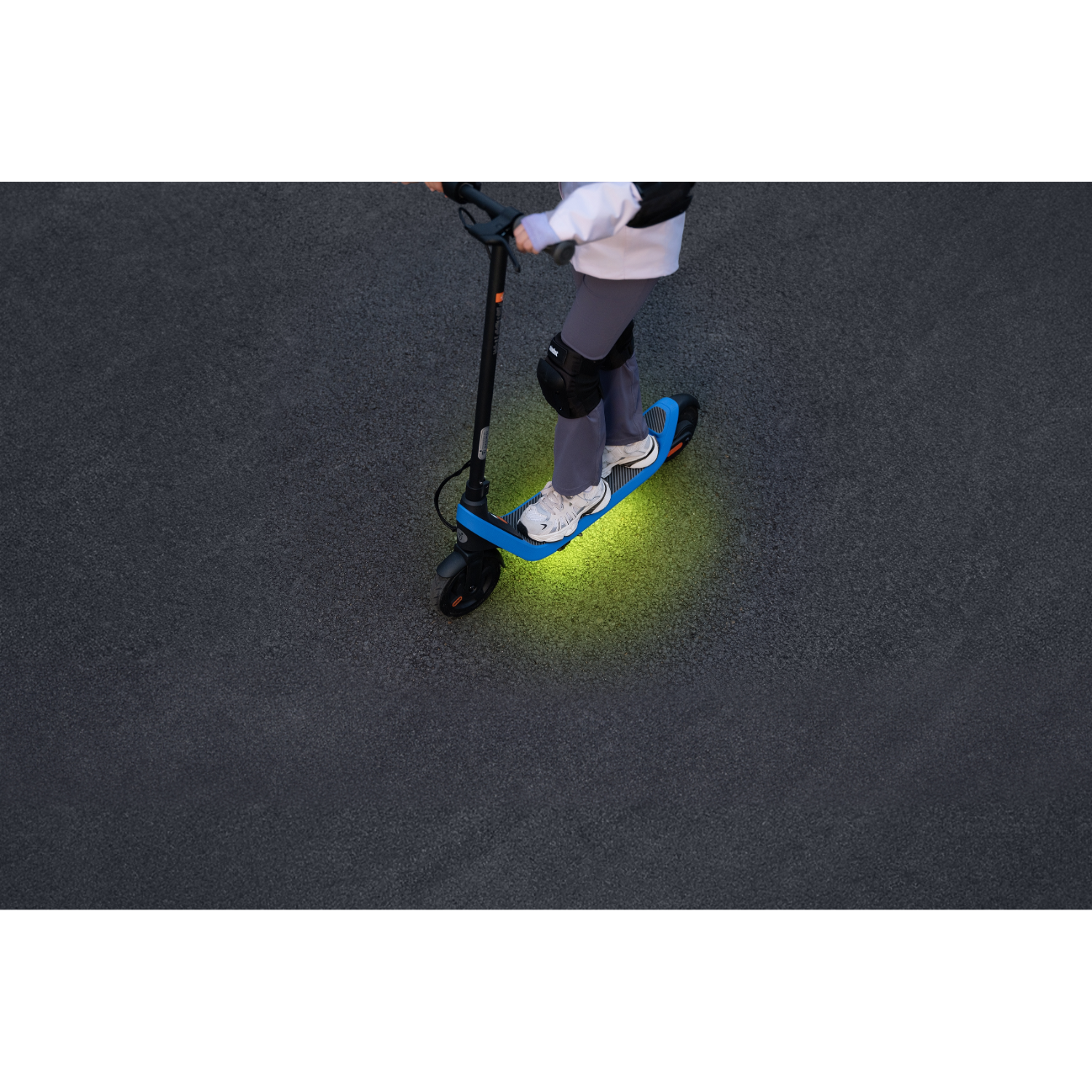 Person riding an electric scooter on a dark gray surface.