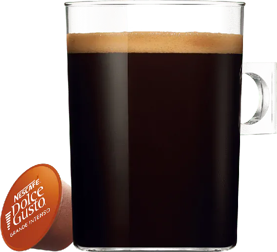 Glasbecher gefüllt mit dunklem Kaffee, Schaum obenauf. Eine Dolce Gusto Kapsel liegt daneben.