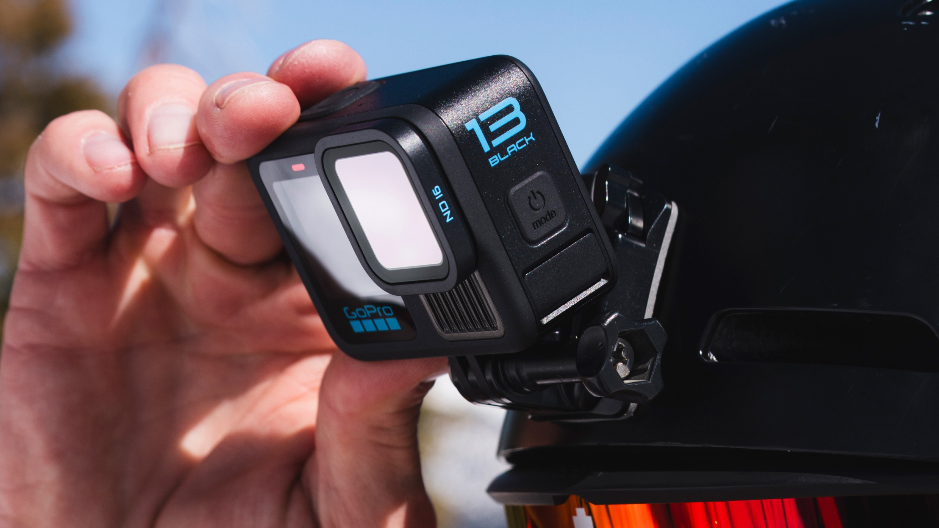 Eine GoPro-Kamera an einem schwarzen Helm befestigt, von Hand gehalten.