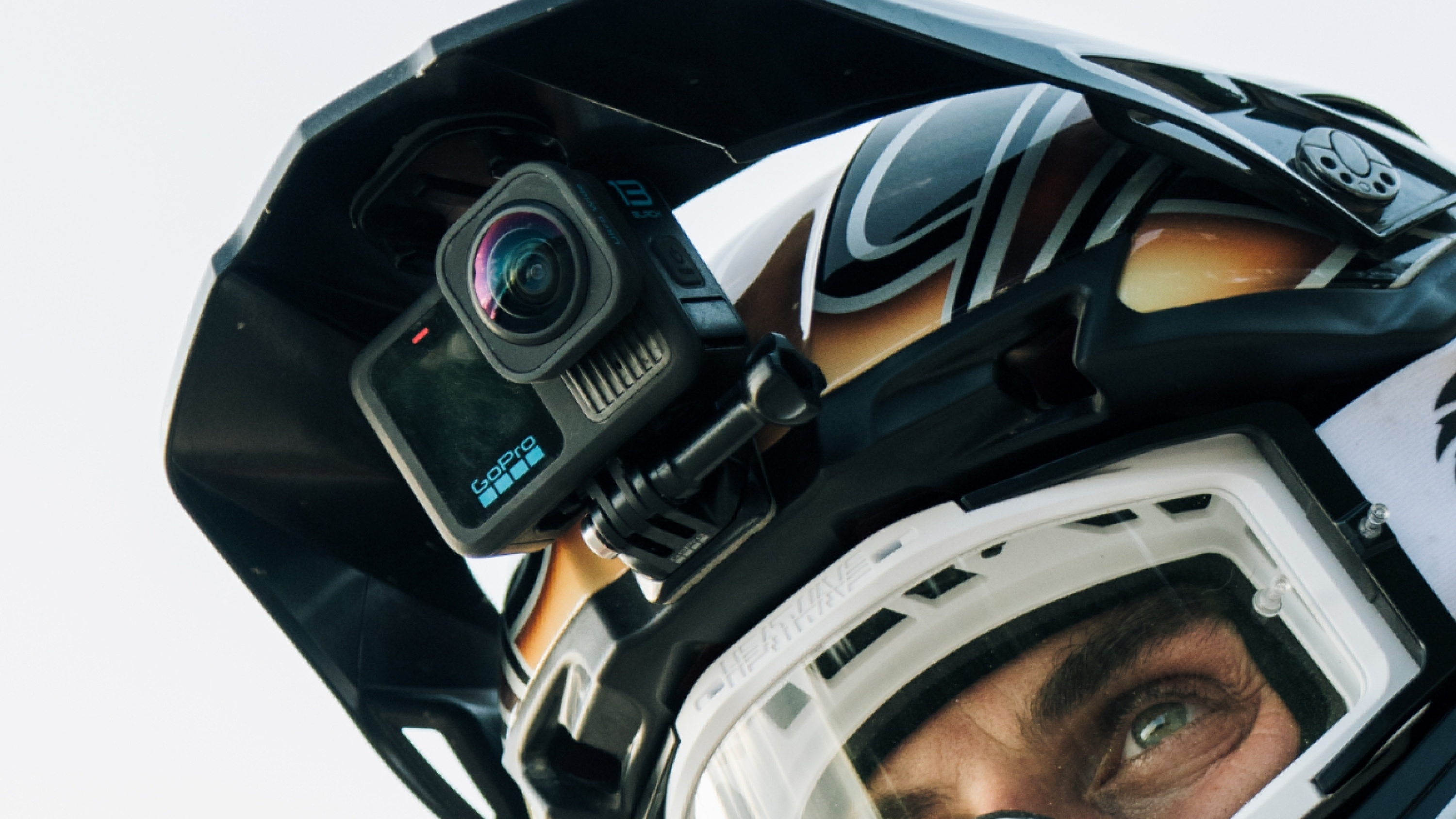 Eine GoPro-Kamera an einem schwarz-weißen Motorradhelm befestigt. Die Kamera ist nach vorne gerichtet.