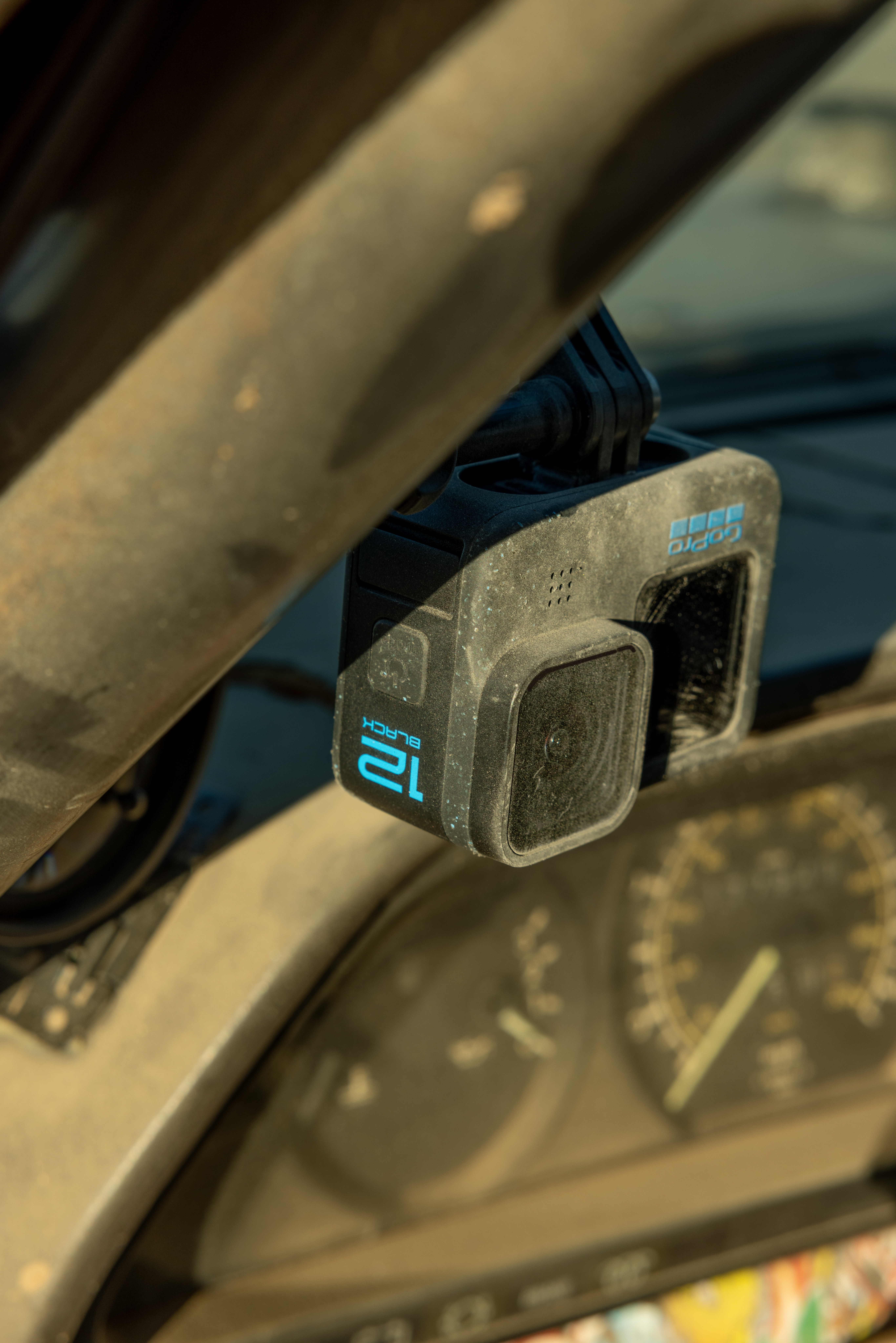 Caméra GoPro 12 Black montée dans une voiture. La caméra est noire et l'intérieur de la voiture est poussiéreux.