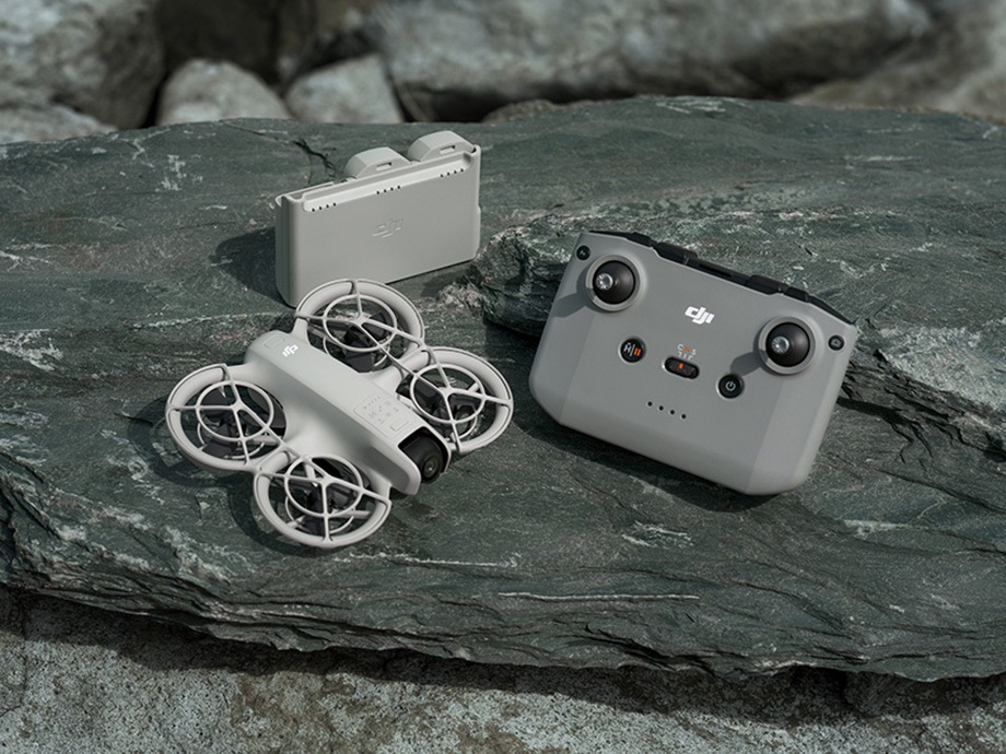 Szary dron, pilot i etui ładujące na skale.