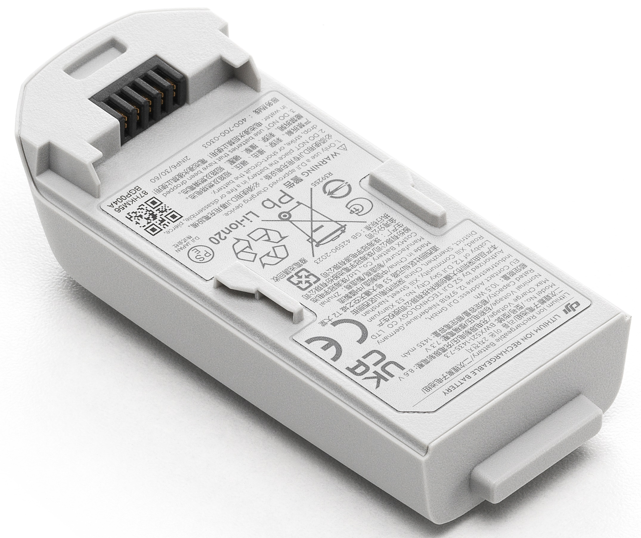 Biała bateria do drona. Tekst, ostrzeżenia i symbole bezpieczeństwa wydrukowane na baterii.