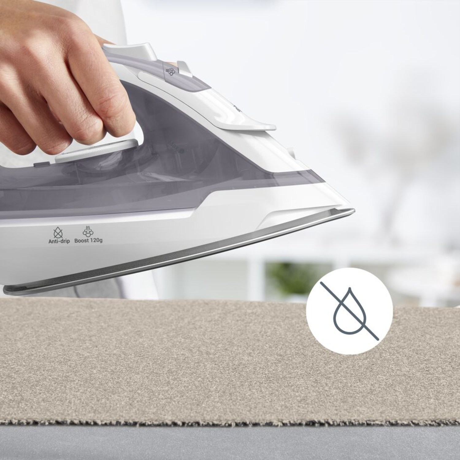An iron ironing a beige fabric on a gray surface. No drip icon.