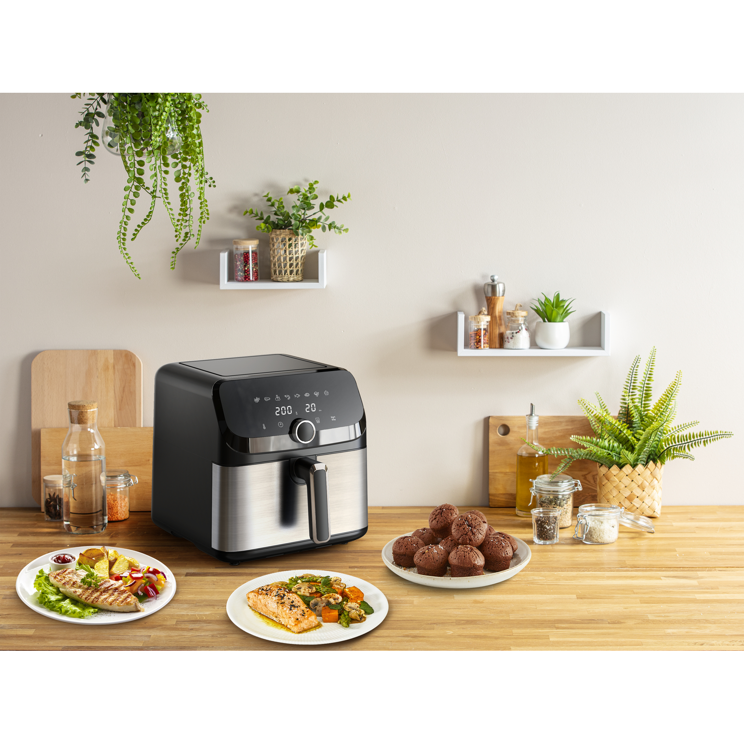A black air fryer with two plates of food and muffins.